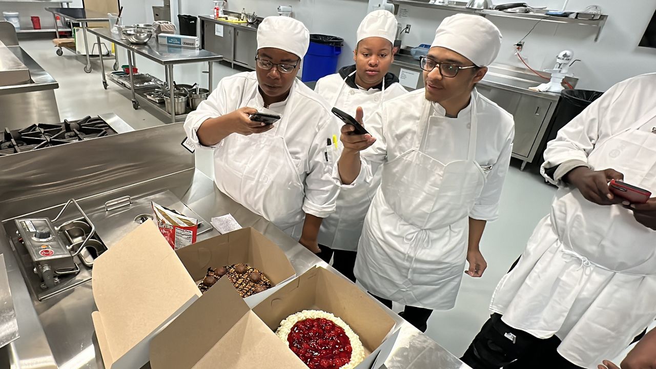 Culinary students taking photos of Daryl's cheesecakes.